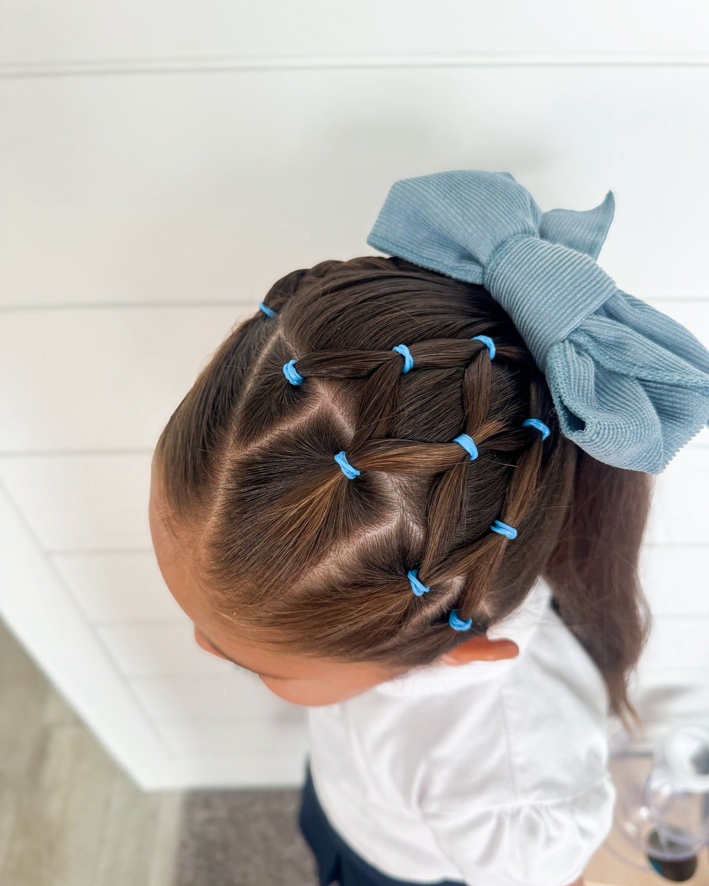 12. Crosscross Elastic Ponytail mit blauer Bogen auf dunkelbraunem Haar (Frisuren für die Schule)