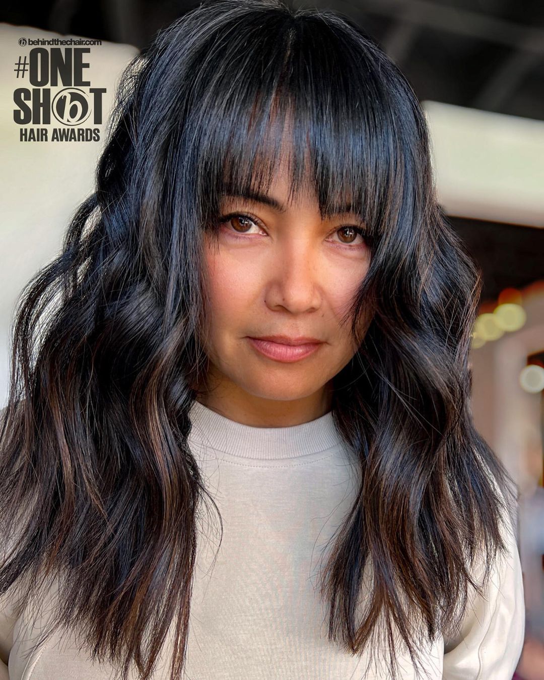 Mittellange Locken mit dezentem braunem Balayage und Pony