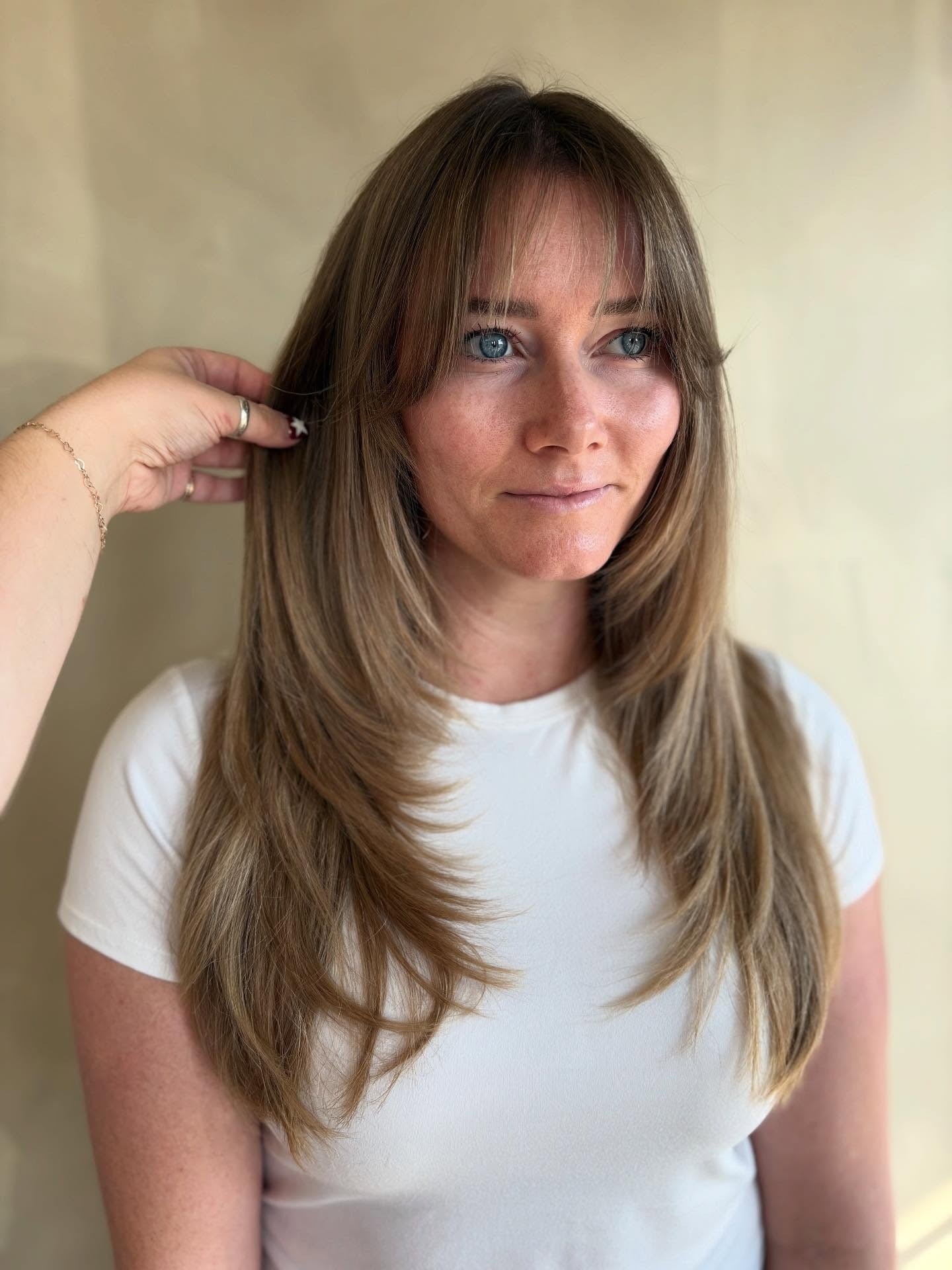 7. Honigbeige Schichten mit zartem Vorhang-Pony (gestuftes Haar mit feinem Pony)