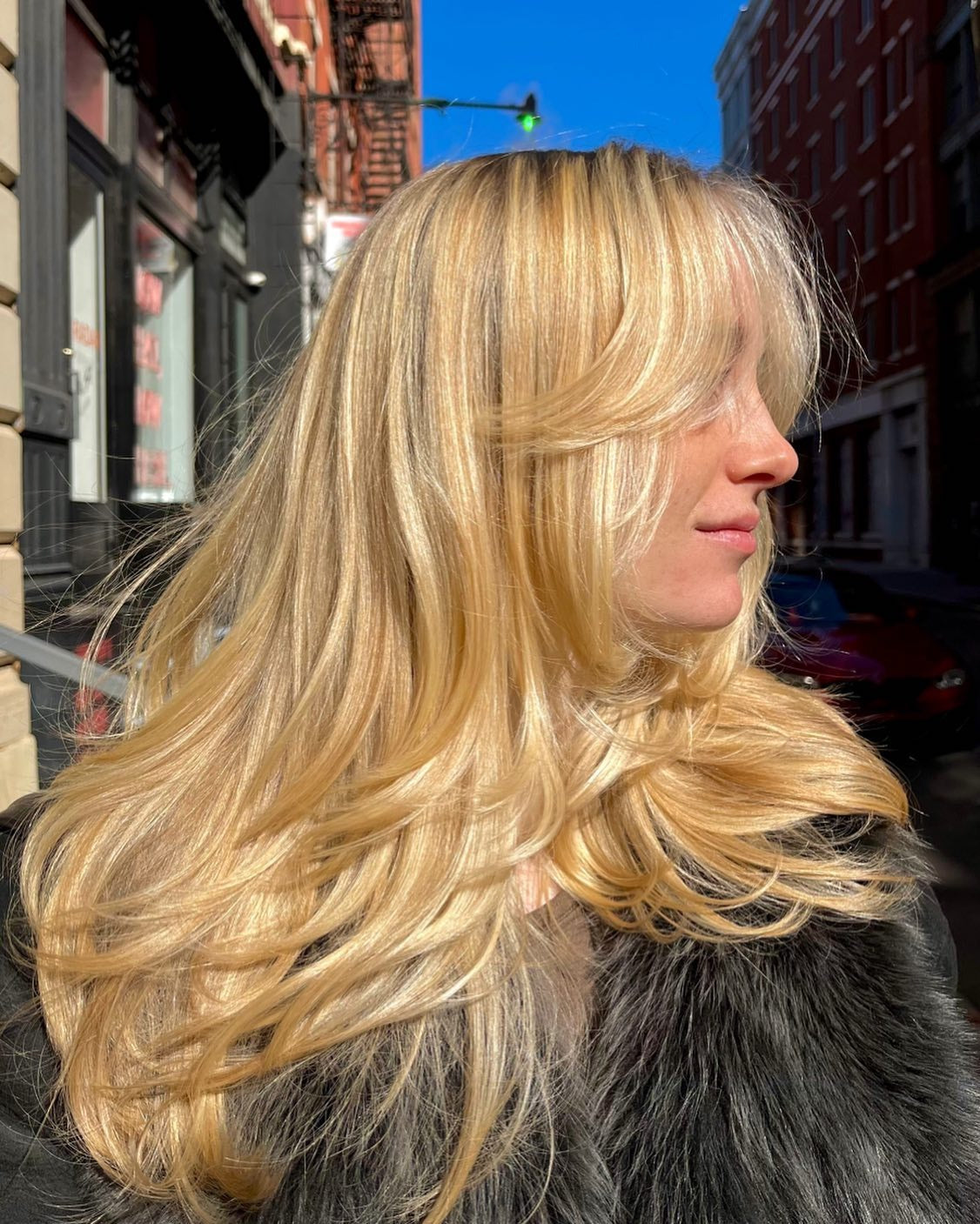 9. Sonnenbeschienene blonde Schichten mit luftigen Strähnen (Wispy Bangs-Frisuren)