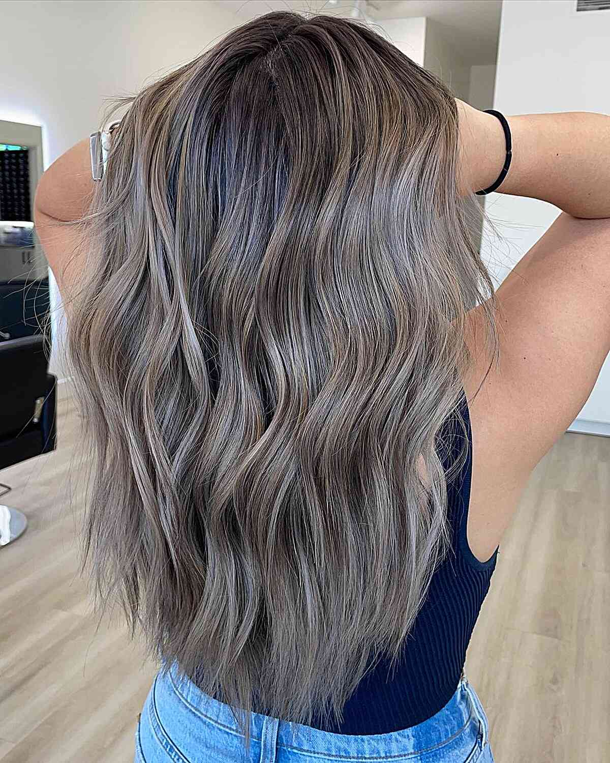 Dunkler aschemblonde Balayage für lange wellige Haare